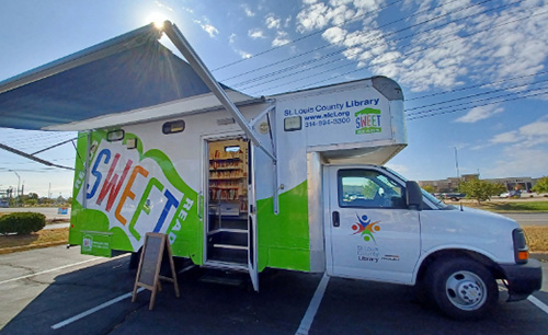 Sweet Reads Bookmobile on a partly cloudy day with awning up and entry door open