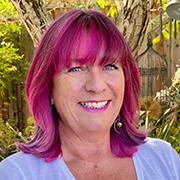 Claire Hennessy smiling with magenta shoulder length hair, white t-shirt, and outdoor background