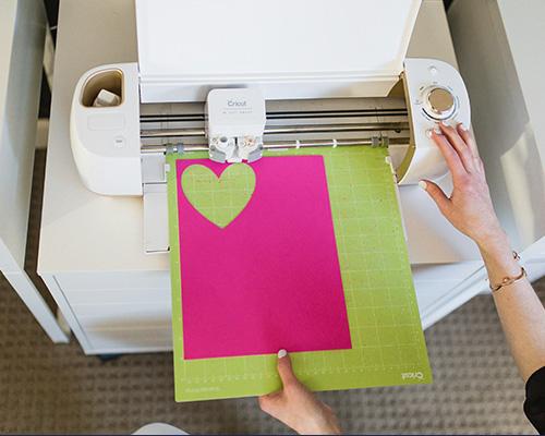 Cricut cutting a heart out of a bright pink sheet