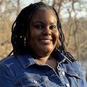 Marissa Brooks smiling outside with the sunlight on her face with her wearing a blue jean jacket